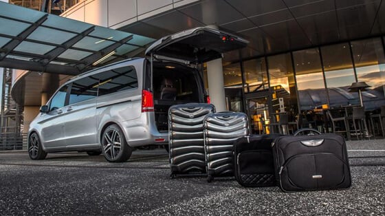 chauffeur vehicle with rear boot open and luggage outside airport