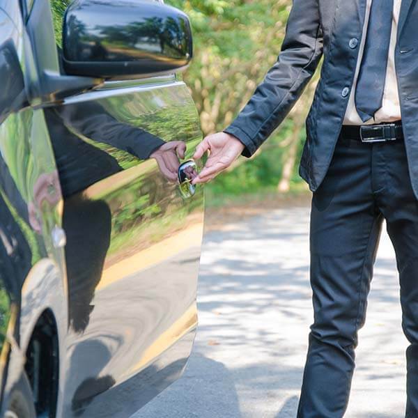 Chauffeur opening MPV door for passenger